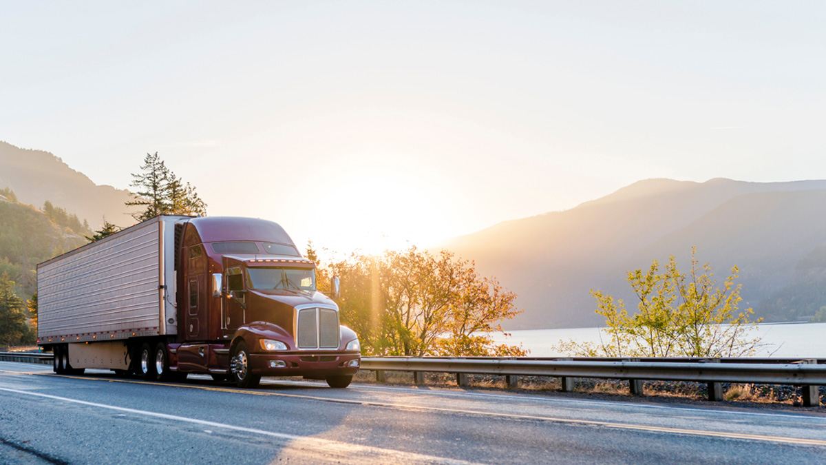 Truck driving on highway next to water and mountains